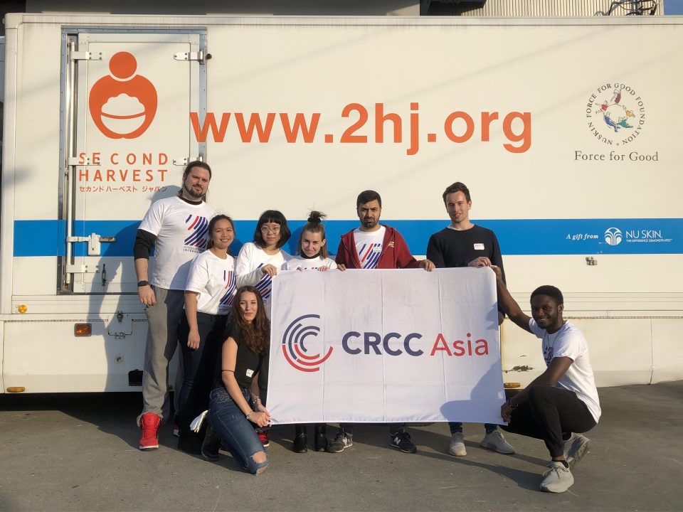 CRCC Asia Tokyo interns stand with the company flag outside of the Second Harvest food bank