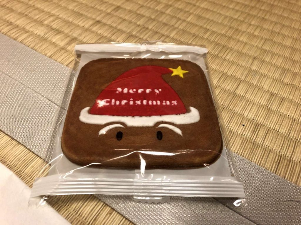 A biscuit reading 'Merry Christmas' with a santa hat - doing an internship in japan