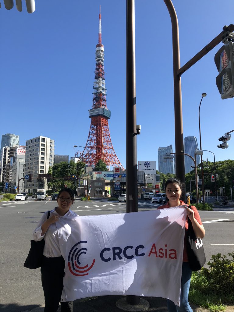 How to Get a Job in Japan - Two interns hold the CRCC Asia flag in front of Tokyo Tower