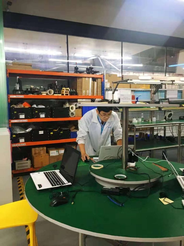 person in white lab coat in lab on a computer