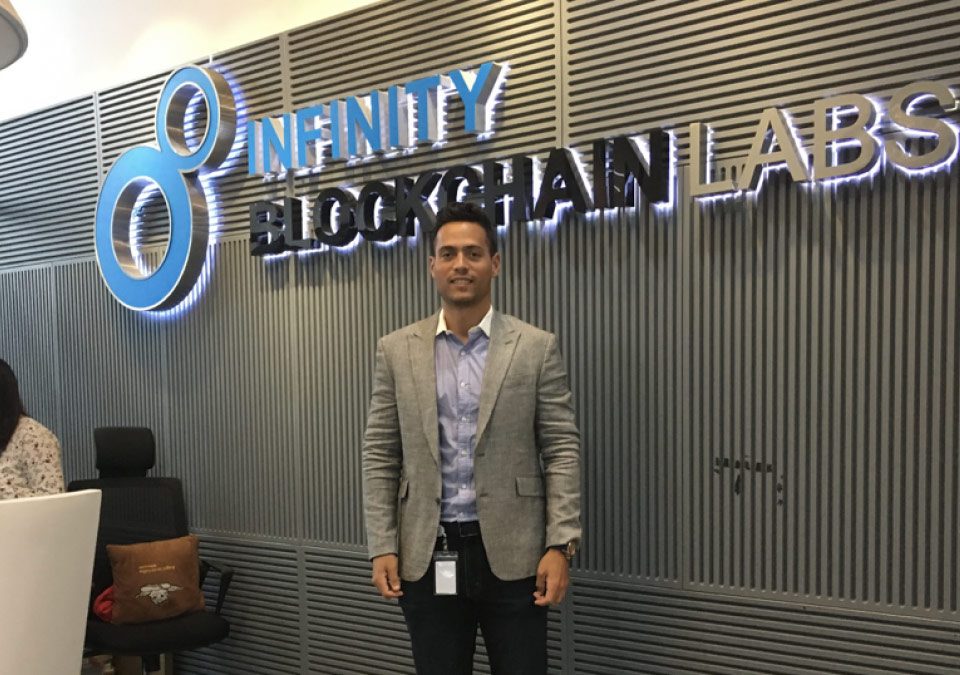 Carloz Marquez standing at reception desk of Infinity Blockchain Labs on his Blockchain Internship with CRCC Asia